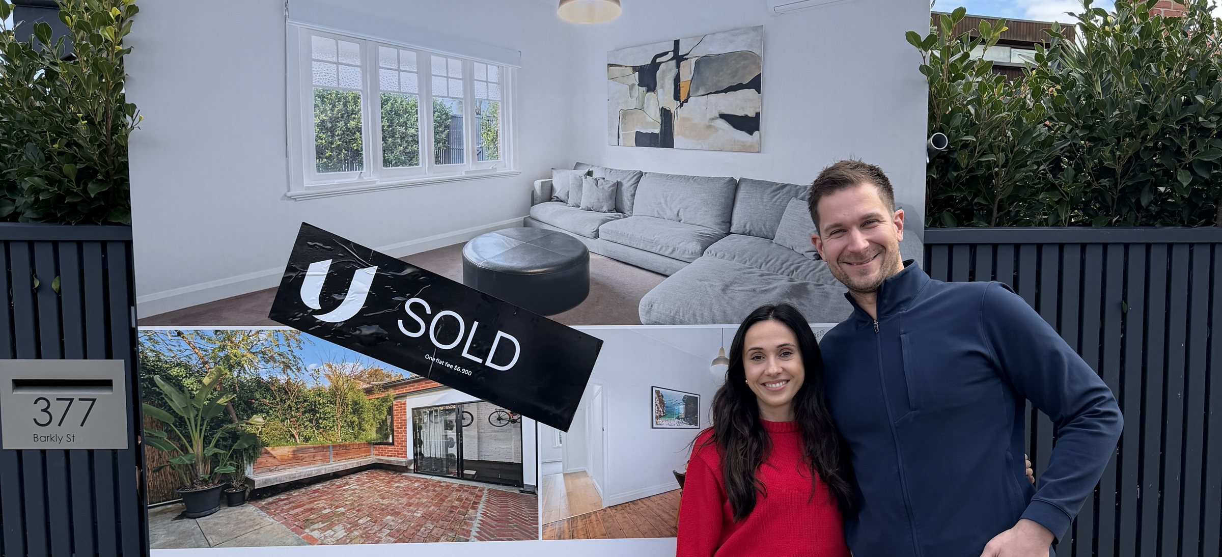 The Unreserved for sale board at 377 Barkly Street, Elwood, with a SOLD sticker across it and the owners standing alongside